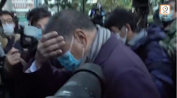 黎智英现身法院应讯：低头躲镜头，忙用手掩面